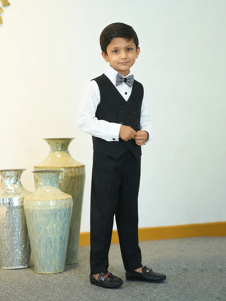 Young boy in a formal outfit standing in front of decorative vases.