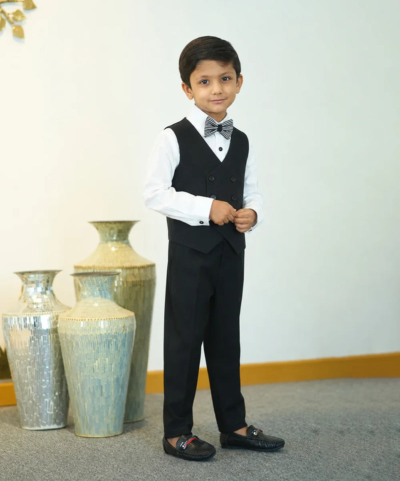Young boy in a formal outfit standing in front of decorative vases.