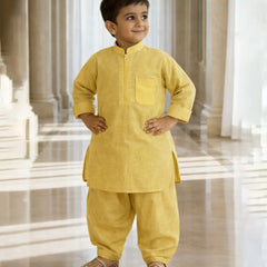 Child wearing a yellow traditional outfit standing in a bright, marble-floored room.