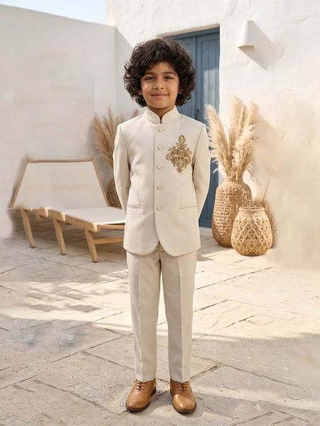 Child in a formal beige suit standing outdoors with decorative elements in the background
