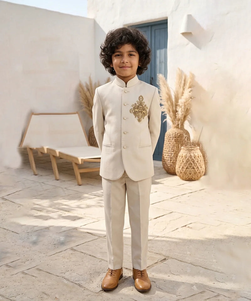 Child in a formal beige suit standing outdoors with decorative elements in the background