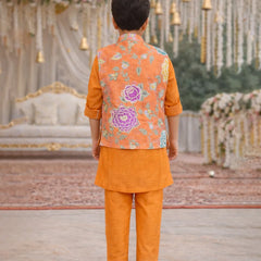 Child wearing an orange traditional outfit with a floral vest in a decorated setting