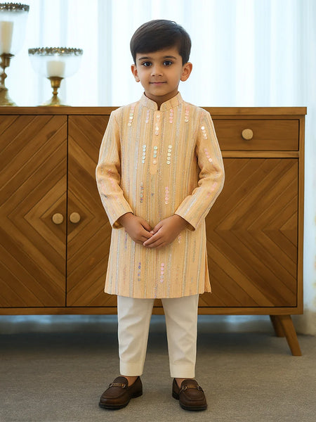 Young boy in traditional outfit standing in front of a wooden cabinet.