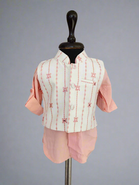 Children's outfit with a white embroidered vest over a pink shirt and shorts on a mannequin against a gray background.