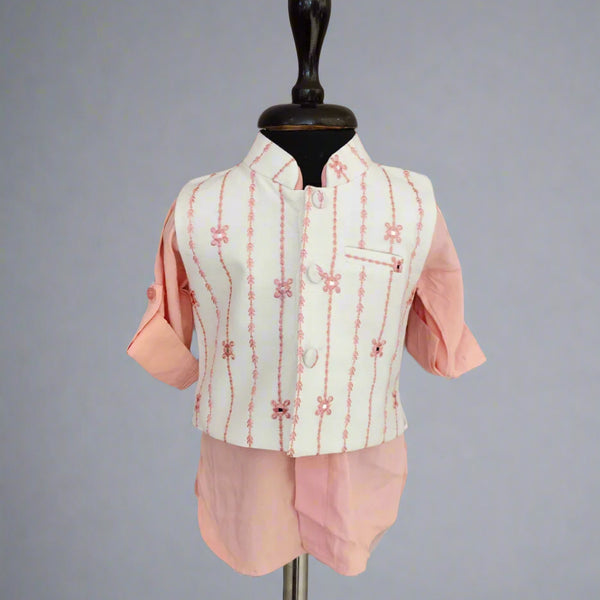 Children's outfit with a white embroidered vest over a pink shirt and shorts on a mannequin against a gray background.