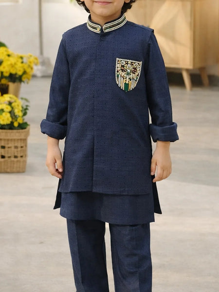 Child wearing a navy blue traditional outfit with decorative pocket, standing indoors.