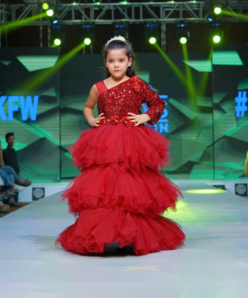 It’s a ruffle layered gown in maroon color that features big sequin bow at the back and floral detailing on the waist.