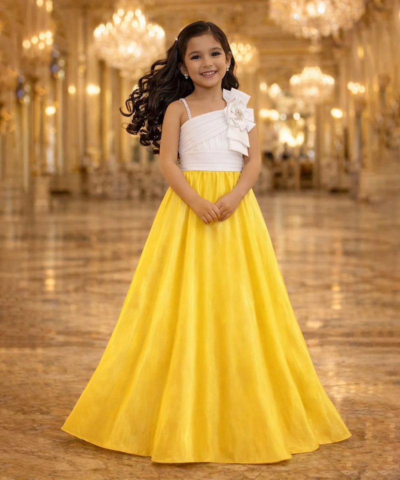 Young girl in a white top and yellow skirt standing in a grand hall with chandeliers.