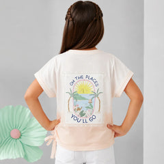 A young girl is shown from behind wearing a cream-colored t-shirt with a colorful tropical beach graphic and the text 'OH THE PLACE'S YOU'LL GO'. She is paired with white pants against a neutral gray background with a decorative mint green paper flower on the left.