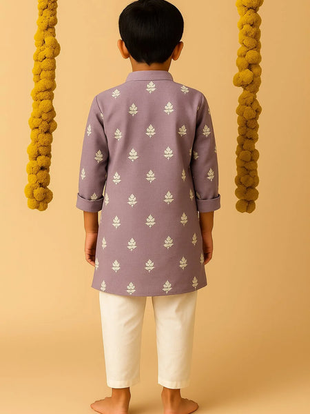 Child wearing a purple kurta with white patterns and white pants on a beige background
