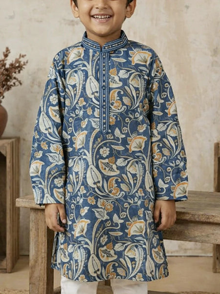 Child wearing a blue patterned kurta standing in a rustic setting.