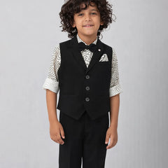 Young boy wearing a formal black vest and pants outfit on a gray background