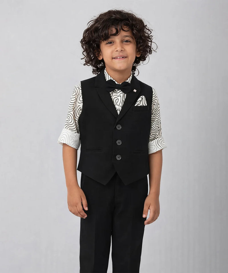 Young boy wearing a formal black vest and pants outfit on a gray background