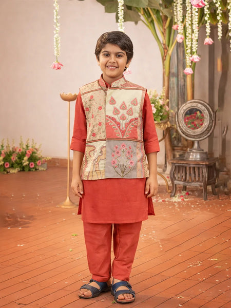 Child wearing a traditional outfit with a floral vest in a decorated indoor setting.