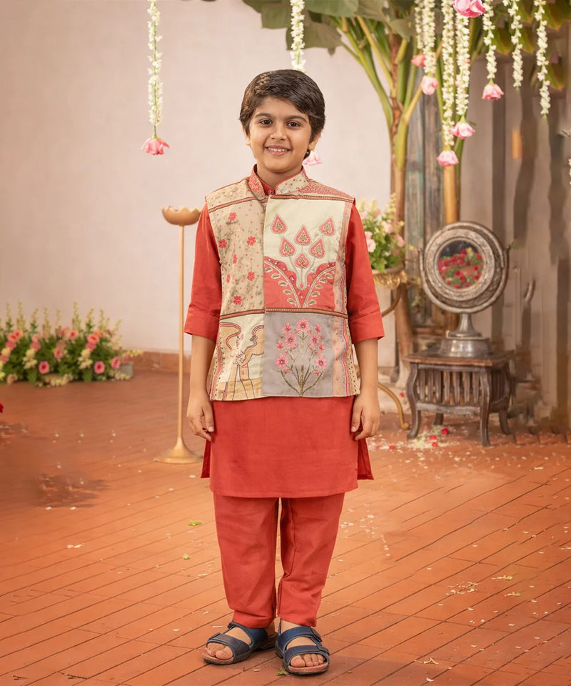 Child wearing a traditional outfit with a floral vest in a decorated indoor setting.