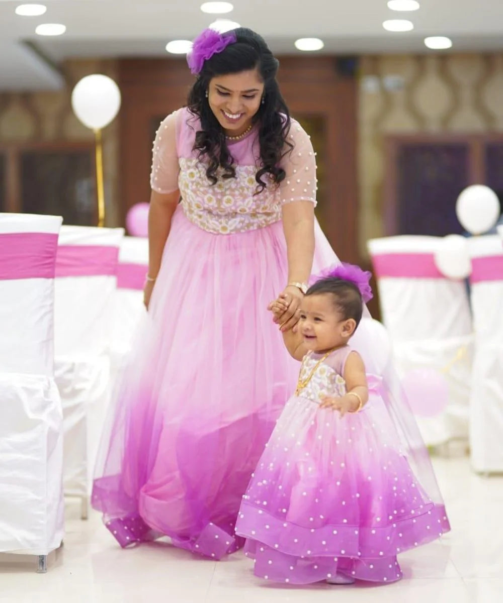 It’s a pink shaded fancy gown for a mother-daughter duo. A perfect children birthday dress and party gown for moms. It features floral detailing on the yoke, pearl detailing and a matching hair accessory.
