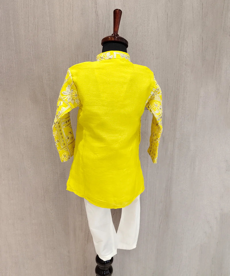 Yellow traditional outfit with white pants on a mannequin against a gray background