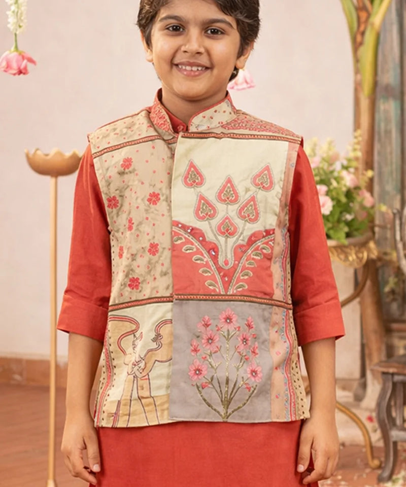 Child wearing a traditional embroidered vest over a red outfit with a decorative background.
