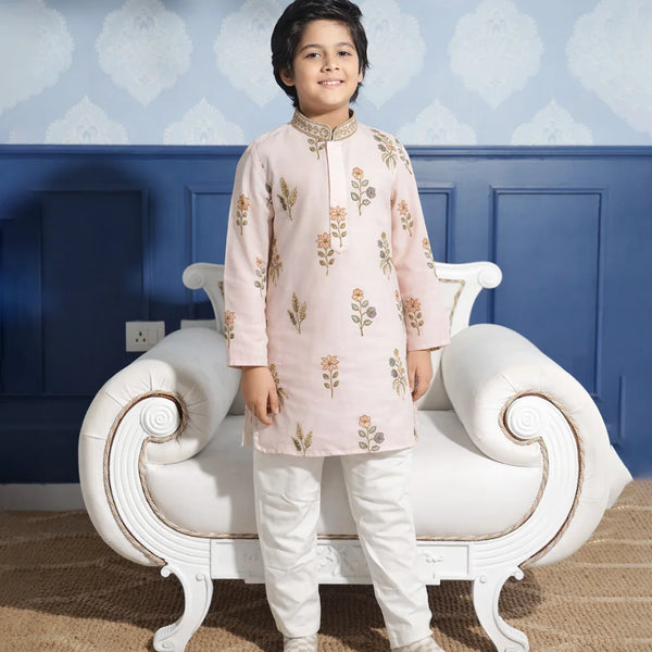 Child wearing a traditional outfit standing in front of a decorative chair with a blue wall background.