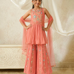 Young girl in a pink traditional outfit with floral embroidery against a white curtain background