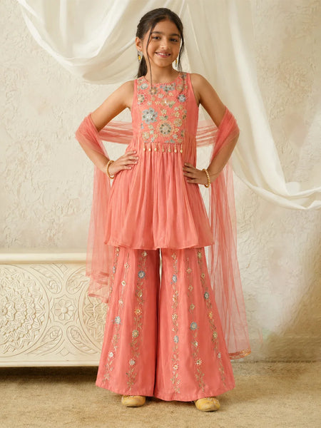 Young girl in a pink traditional outfit with floral embroidery against a white curtain background