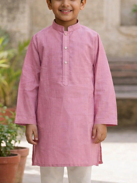 Child wearing a pink kurta with a blurred outdoor background