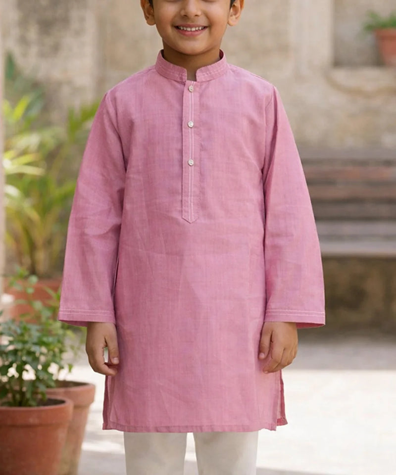 Child wearing a pink kurta with a blurred outdoor background