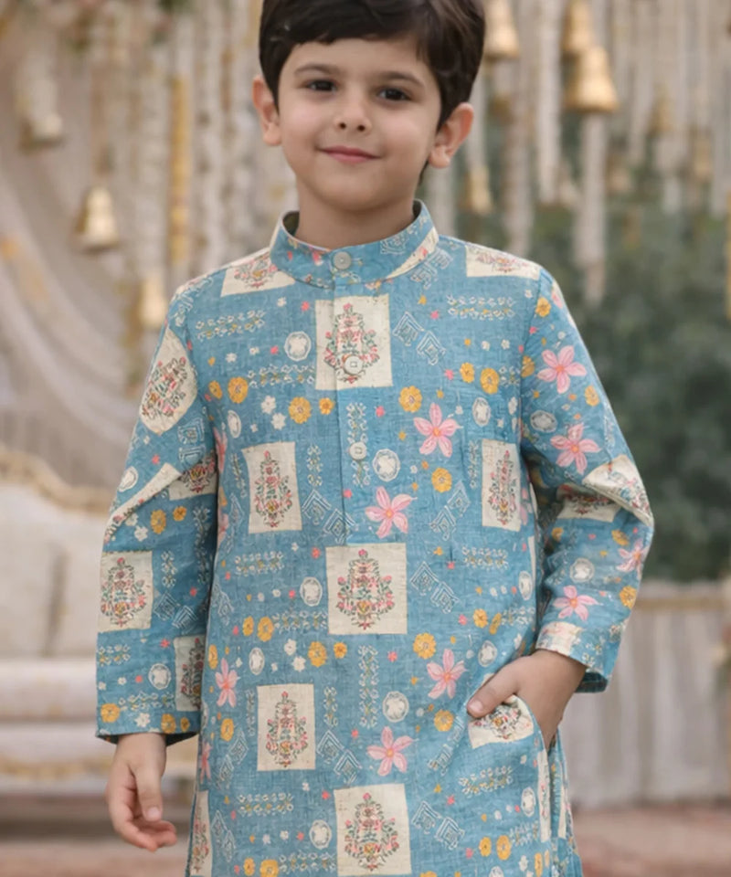 Child wearing a blue traditional outfit with floral and geometric patterns.