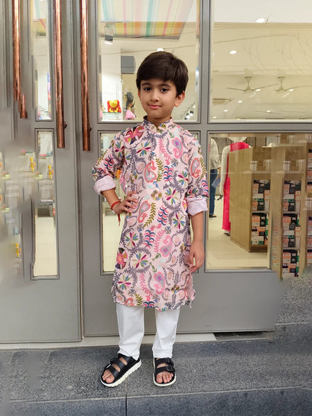 Child wearing a floral kurta standing in front of a store entrance.