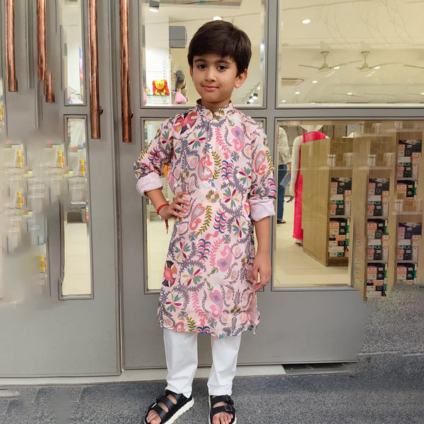 Child wearing a floral kurta standing in front of a store entrance.