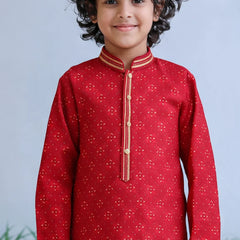 Child wearing a red traditional outfit with gold accents against a light blue background