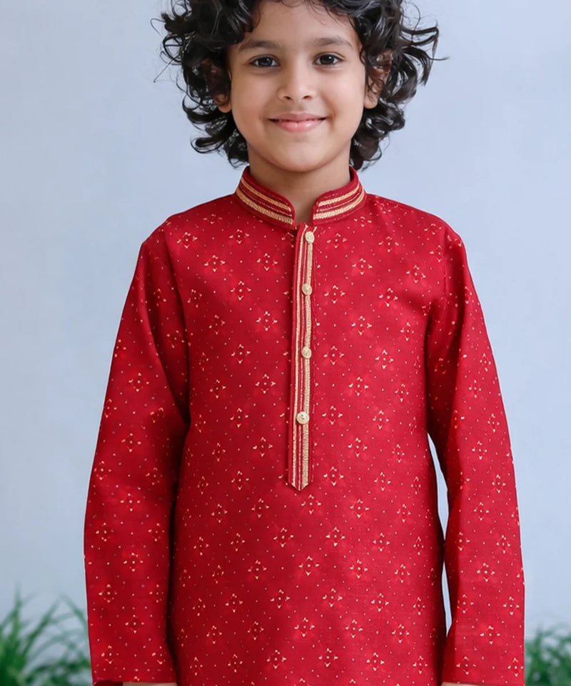 Child wearing a red traditional outfit with gold accents against a light blue background