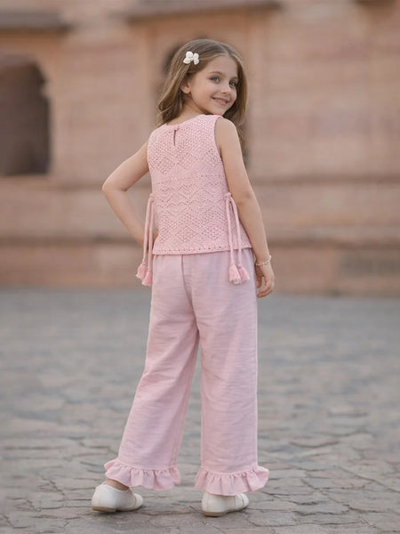Young girl in a pink outfit standing on a stone pavement.