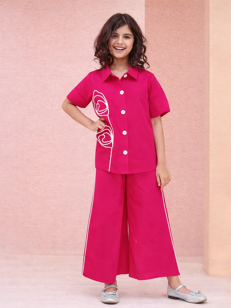 Young girl wearing a pink outfit with white buttons and trim against a pink background