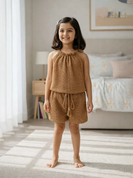 Young girl wearing a brown knitted outfit standing in a bedroom.