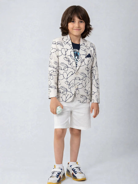 Child wearing a patterned blazer and white shorts on a plain background