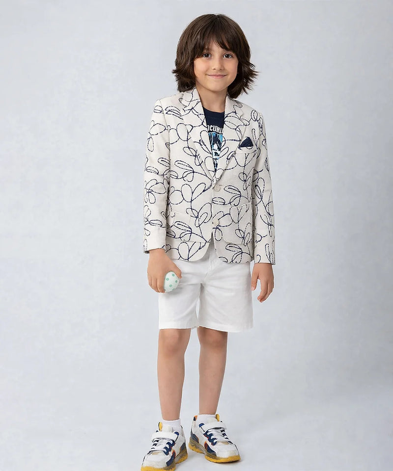 Child wearing a patterned blazer and white shorts on a plain background