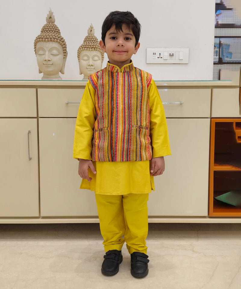 It is a yellow color plain kurta pajama with a multi striped jacket