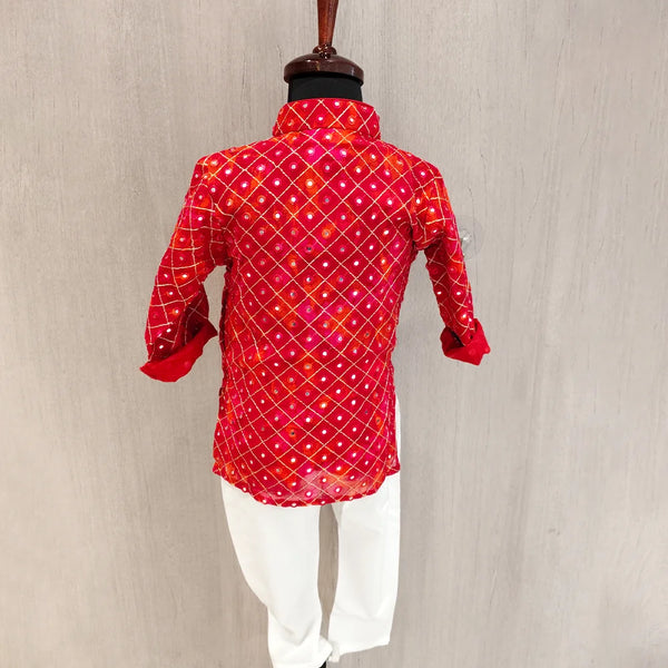 Red patterned shirt with white pants on a mannequin against a beige background