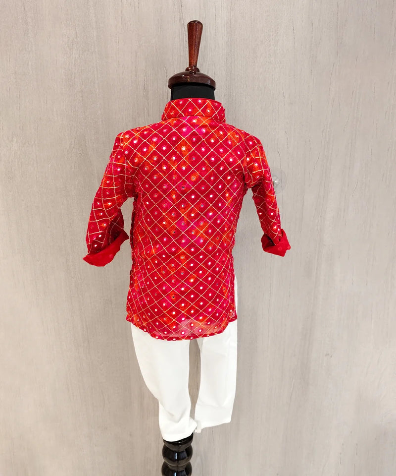 Red patterned shirt with white pants on a mannequin against a beige background