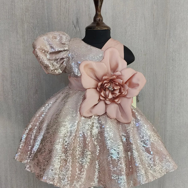 Sparkly dress with a large pink flower on a mannequin against a gray background
