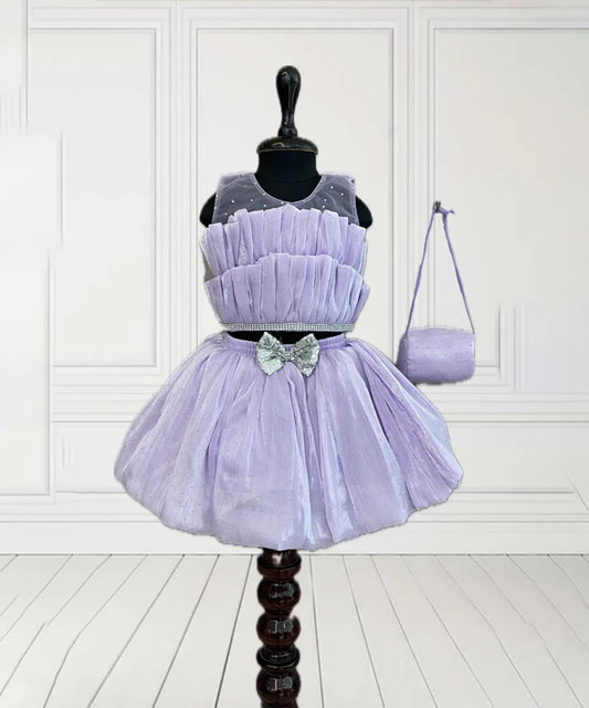 This purple coloured kids birthday wear dress consists of a fancy crop top with a back closure and a balloon skirt. It is paired up with a matching handbag. It features a pleated yoke, rhinestone belt at the bottom of the top, bow detailing on the waist and Siroski work all over the dress.