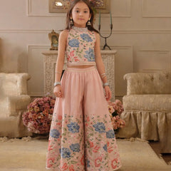 Young girl in a floral top and pink pants standing in an elegant room.