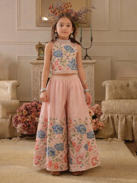 Young girl in a floral top and pink pants standing in an elegant room.