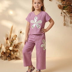 Young girl wearing a pink outfit with floral designs in a warm-toned setting
