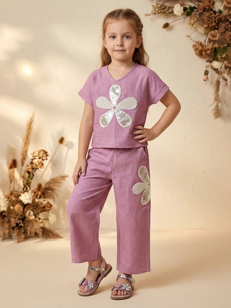 Young girl wearing a pink outfit with floral designs in a warm-toned setting