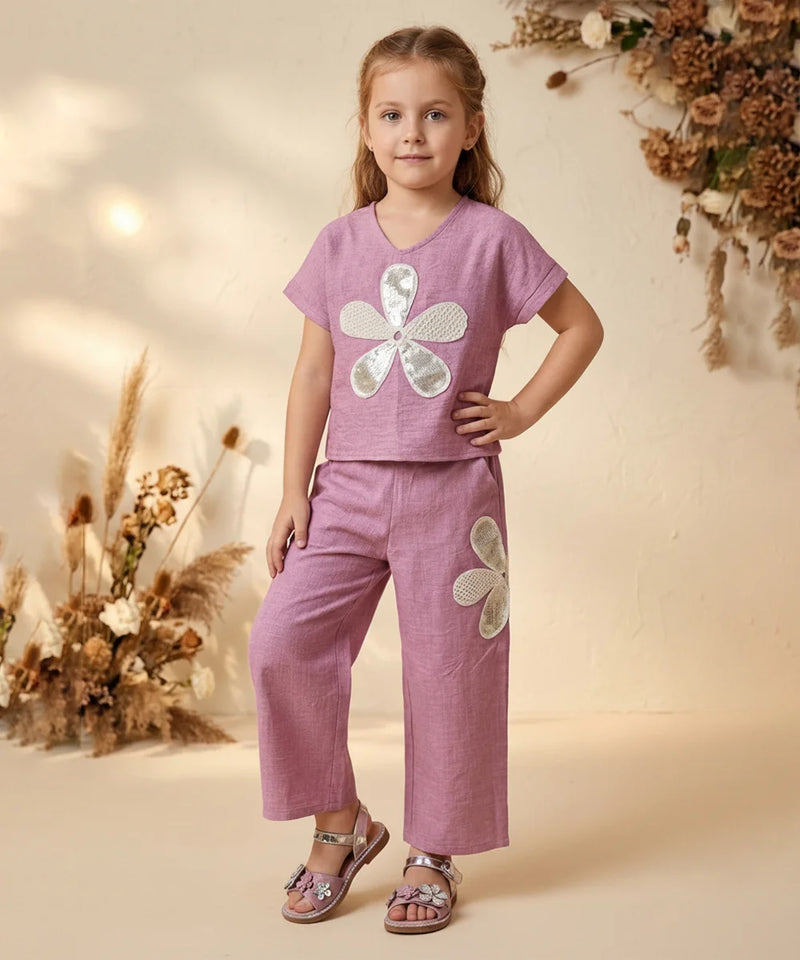 Young girl wearing a pink outfit with floral designs in a warm-toned setting