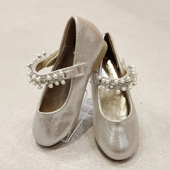 Pair of silver glittery shoes with decorative straps on a light background