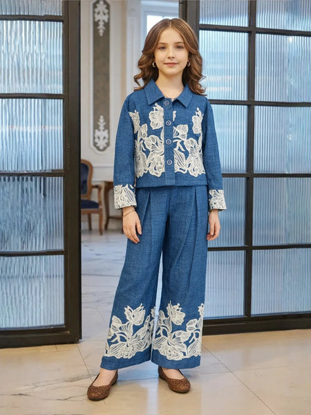 Person wearing a blue outfit with white floral embroidery in an indoor setting.