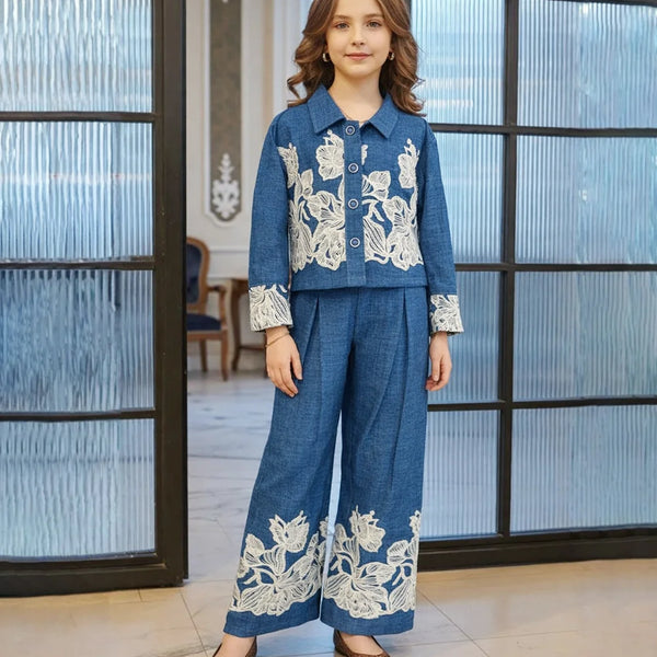 Person wearing a blue outfit with white floral embroidery in an indoor setting.